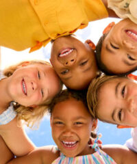 Group Of Multi-Cultural Children Friends Linking Arms Looking Down Into Camera